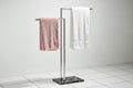 Gold towel rack with black towels against a stone wall
