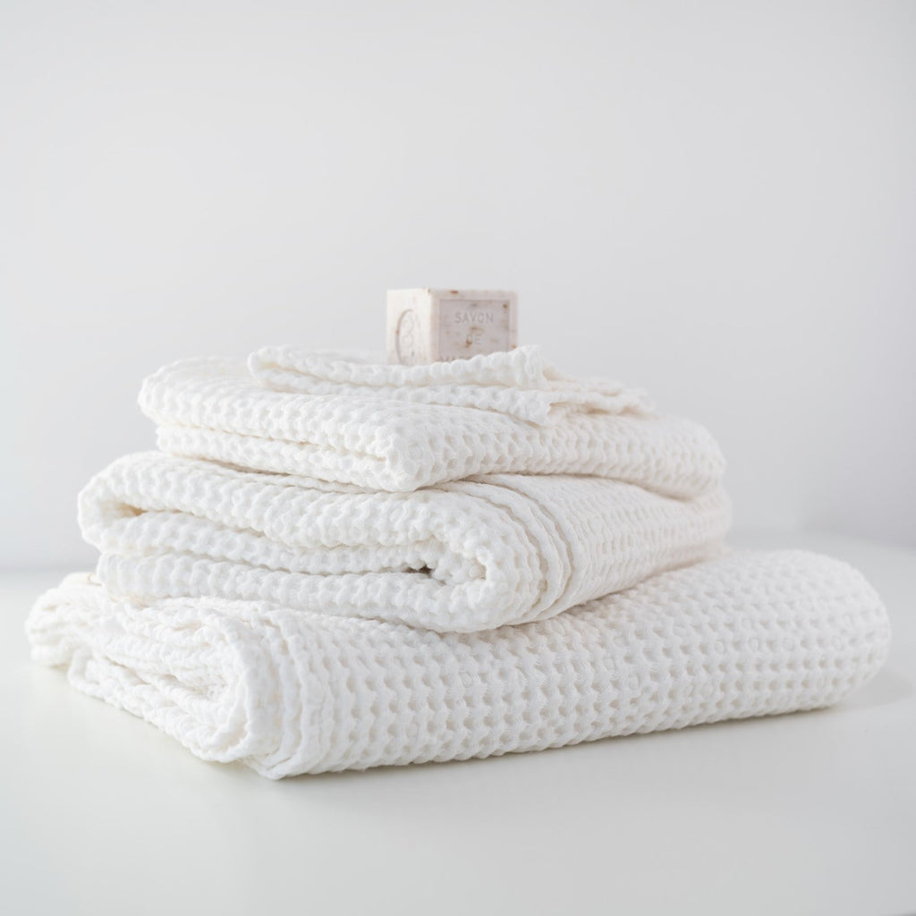 Stack of white textured towels on a light gray surface with a neutral background