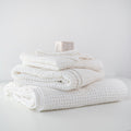 Stack of white textured towels on a light gray surface with a neutral background