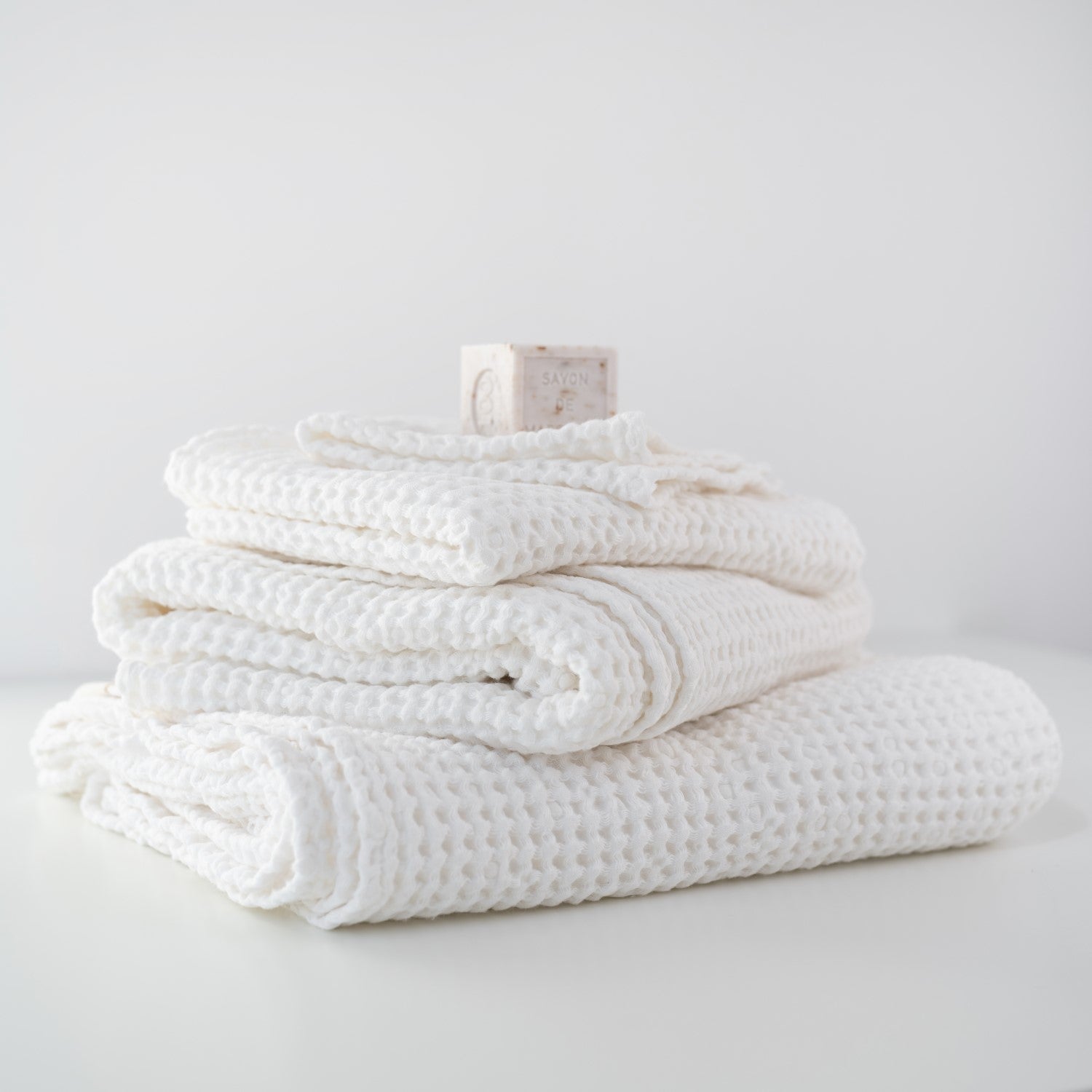 Stack of white textured towels on a light gray surface with a neutral background