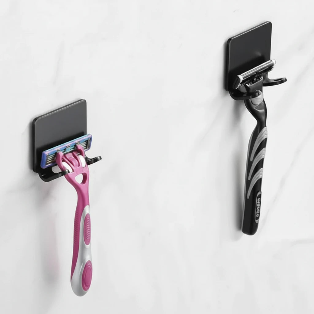 Three black wall-mounted hooks displayed on a light gray marble wall, with two holding razors.