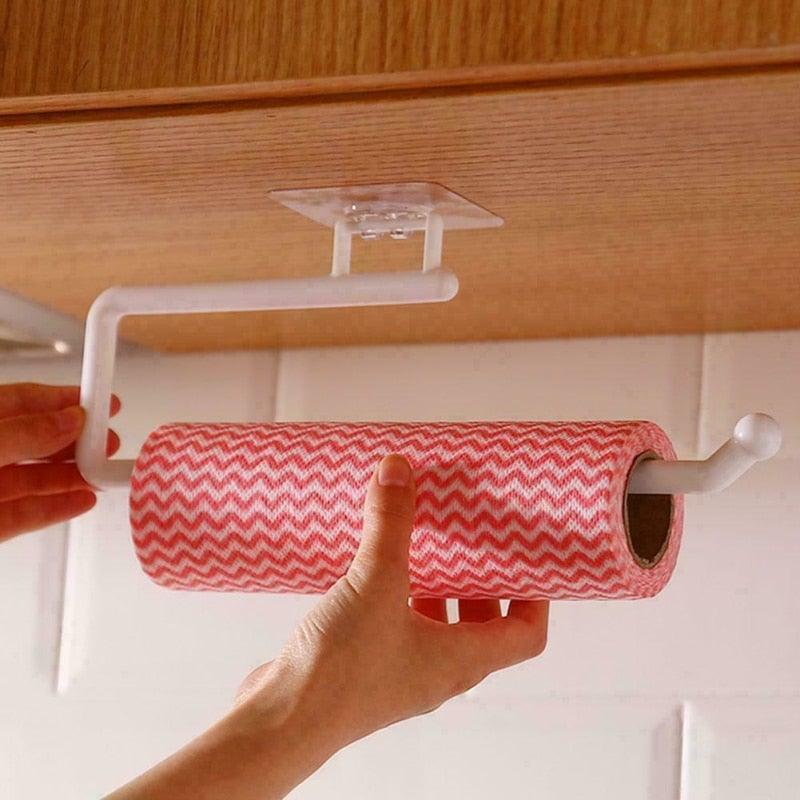 Person using a paper towel holder with a red and white zigzag patterned roll underneath a wooden cabinet.